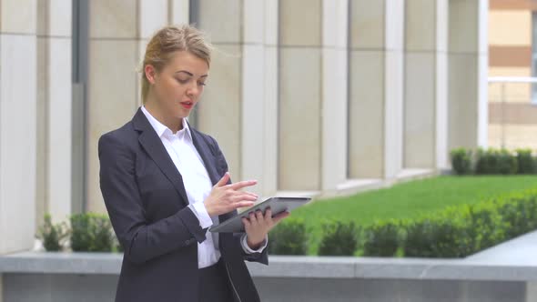 Elegant Business Woman with Tablet Computer Near Office Building