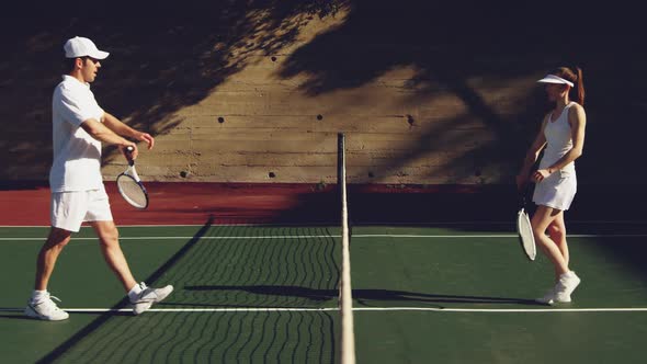 Woman and man playing tennis on a sunny day