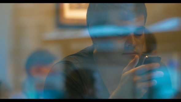 Young Man Behind The Glass Texting On Smartphone alt