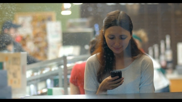 Woman Exchanging Messages On Cell In Cafe alt