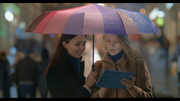 Female Friends Using Touch Pad On Rainy Evening In alt