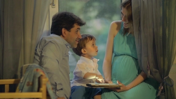 Little Child And Parents With Pad At Home