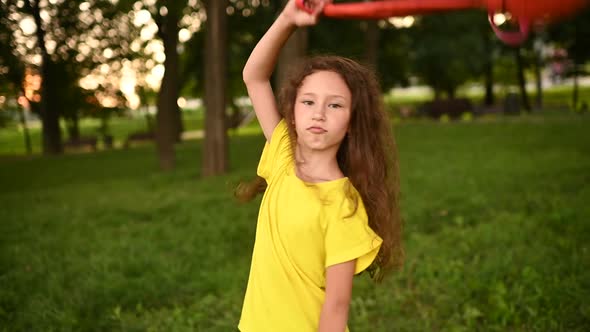 a Schoolgirl Girl with Curly Hair Rejoices at the Beginning of the Holidays and Throws Up a School