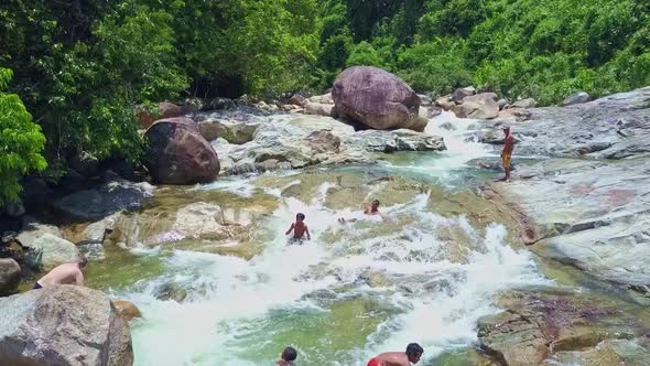 Drone Shows Local Children and Tourists Slide on Rapids Stones