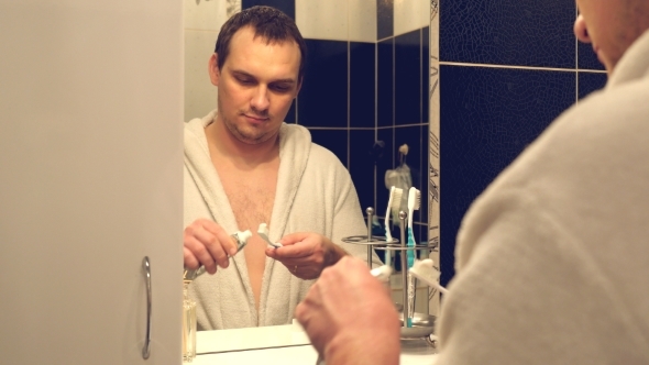 Man In a Bathrobe Washing His Teeth In Bathroom