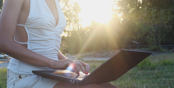 Girl on Nature at the Sunset Typing on the Laptop