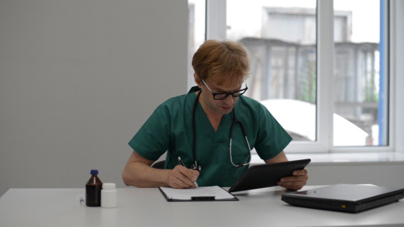 Doctor Doing Paper Work, Using Tablet 