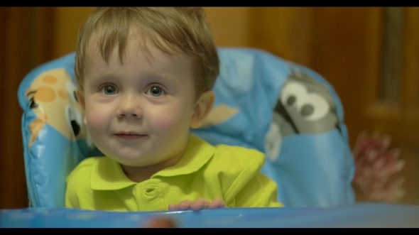 Lovely Smiling Boy Sitting At Feeding Table alt