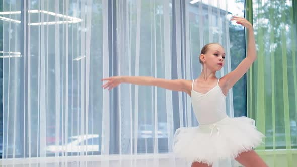 Little Ballerina in Tutu Dances Ballet Near Window in Studio