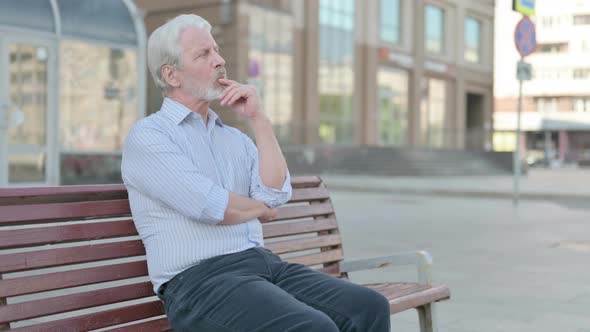 Pensive Old Man Thinking While Sitting Outdoor on Bench