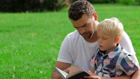 Father And Son Reading Book In Park alt