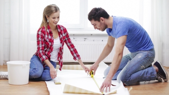 Happy Couple Cutting Wallpaper With Knife At Home alt