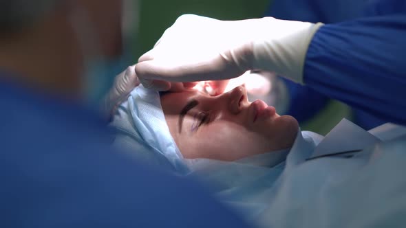 Closeup Side View Young Woman on Surgery Bed with Expert Doctor Cleaning Eyelid Dissection in Slow