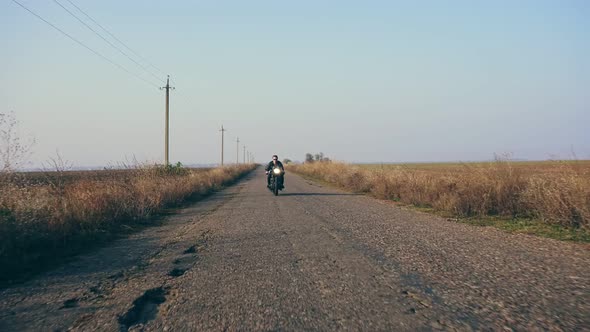 Stylish Cool Young Man in Sunglasses and Leather Jacket Approaching While Riding a Motorcycle on a