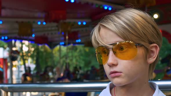 A Frustrated Teenage Guy Stands By the Carousels He Cannot Ride the Carousels Because He is Punished