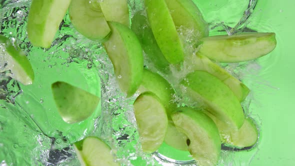 Super Slow Motion Shot of Green Apple Cuts Falling and Splashing Into Water at 1000Fps