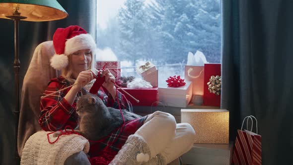 Woman Relaxing in Cozy Home with Cute Cat on Her Lap and Knitting Red Needles