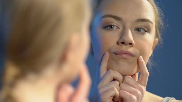 Upset Female Teenager Looking in Mirror, Noticing Pimples, Skin Imperfection