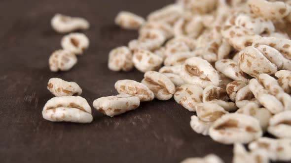 Puffed spelt wheat on a dark wooden background. Falling in slow motion