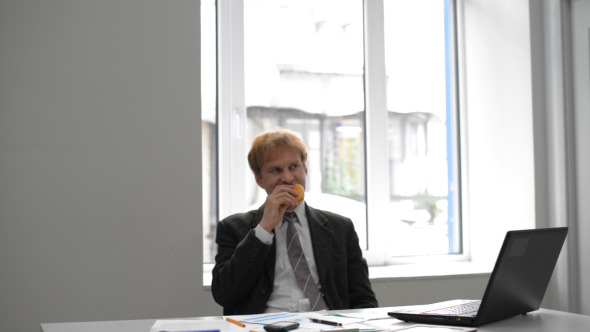 Businessman Eating Burger at Work