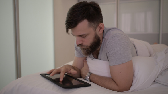 Beard Man Using Tablet in Bed