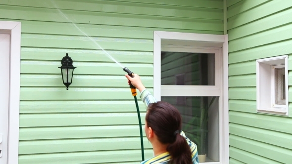 Man And Woman Washing Wall Of A House