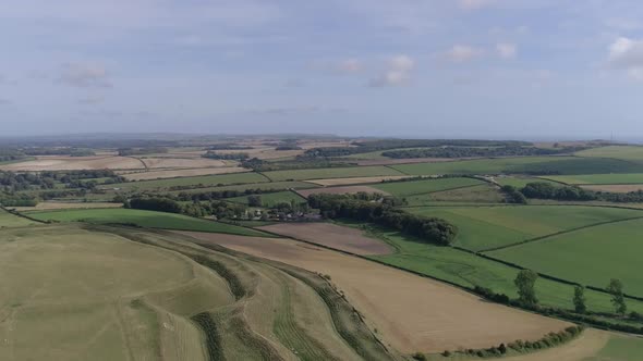 High up aerial tracking forward over Maiden Castle looking south, Sea is just visible on the horizon