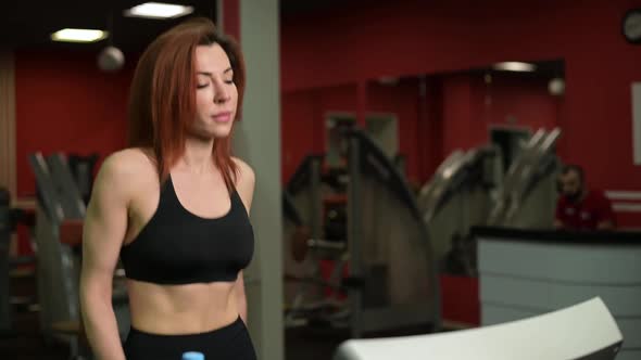 Young woman adjusts the treadmill routine for her type of workout, close-up
