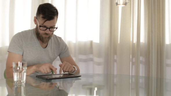 Young Man Typing on Tablet alt