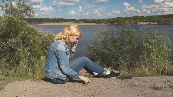 Girl Speaks on the Phone Near the River