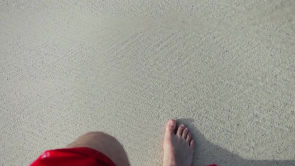 Young Man Walking Barefoot On The Beach