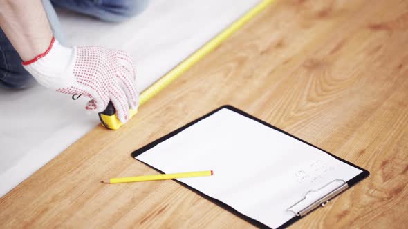 Close Up Of Man Measuring Flooring And Writing 8