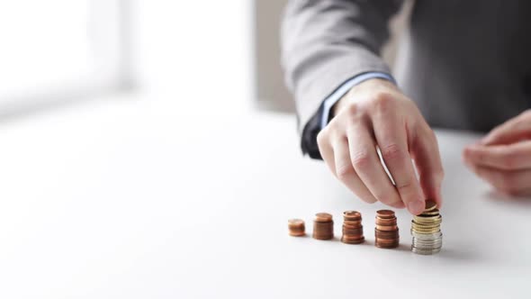 Close Up Of Businessman Putting Coins Into Columns 3