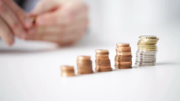 Close Up Of Businessman Putting Coins Into Columns 8