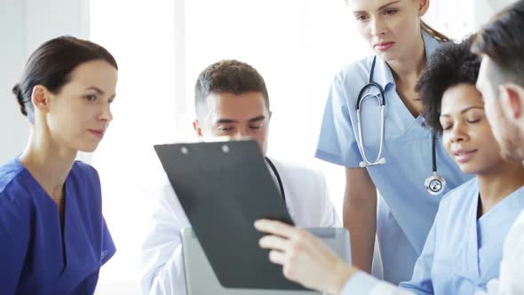 Group Of Doctors With Clipboard Talking At Clinic 2