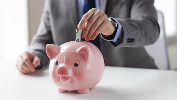 Close Up Of Man Putting Money Into Piggy Bank 4