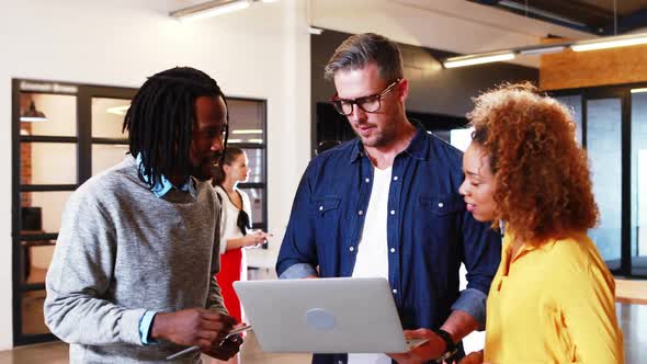 Business people discussing over laptop