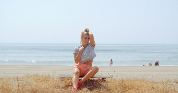 Woman Sitting On Her Skateboard At The Beach