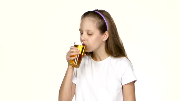 Little Girl Drinks Apple Juice and Admires It. White Background