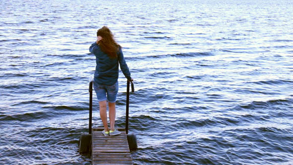 Girl Sitting on a Pier Looking at the Ocean alt