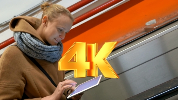 Woman On Escalator Using Tablet Computer alt