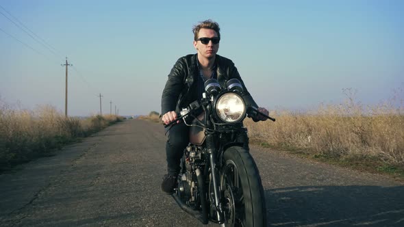 Closeup View of a Stylish Cool Young Man in Sunglasses and Leather Jacket Riding Motorcycle on a