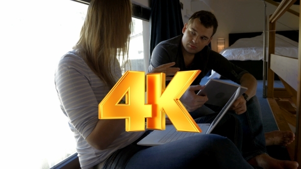 Man And Woman Talking While Using Pad And Laptop
