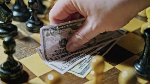 Money in US dollar bills on an old chessboard with retro chess pieces