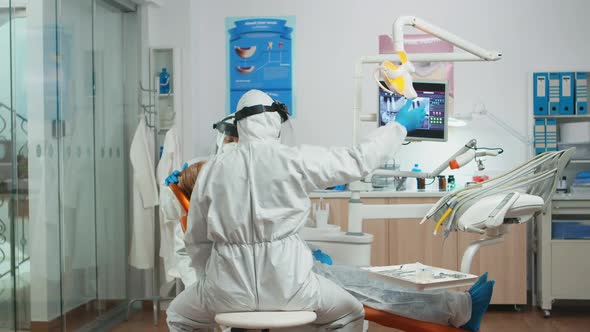 Dentist and Assistant in Coverall Examining Mouth of Patient