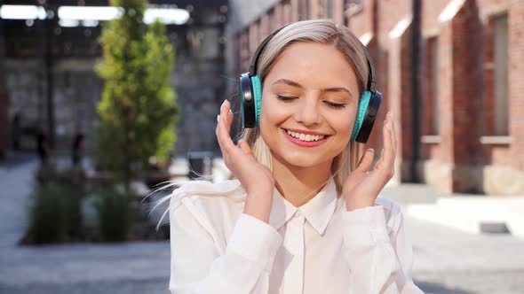 Woman Listening to Music in Wireless Headphone Showing OK Sign with Thumb Up