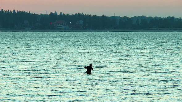 A Man Checks Fishing Net In the Sea Before Dawn