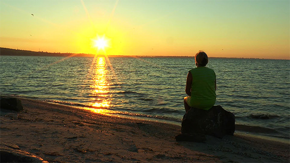 A Woman Looking at the Sunrise Over the Sea alt