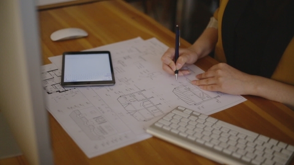 Young Female Architect Working On Blueprint