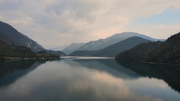 Aerial view over the Ledro lake, Trentino, Italy. Drone over the lake with reflected sky in the wate